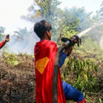 Un adolescente indonesiano vestito da supereroe aiuta a spegnere i fuochi nel Borneo