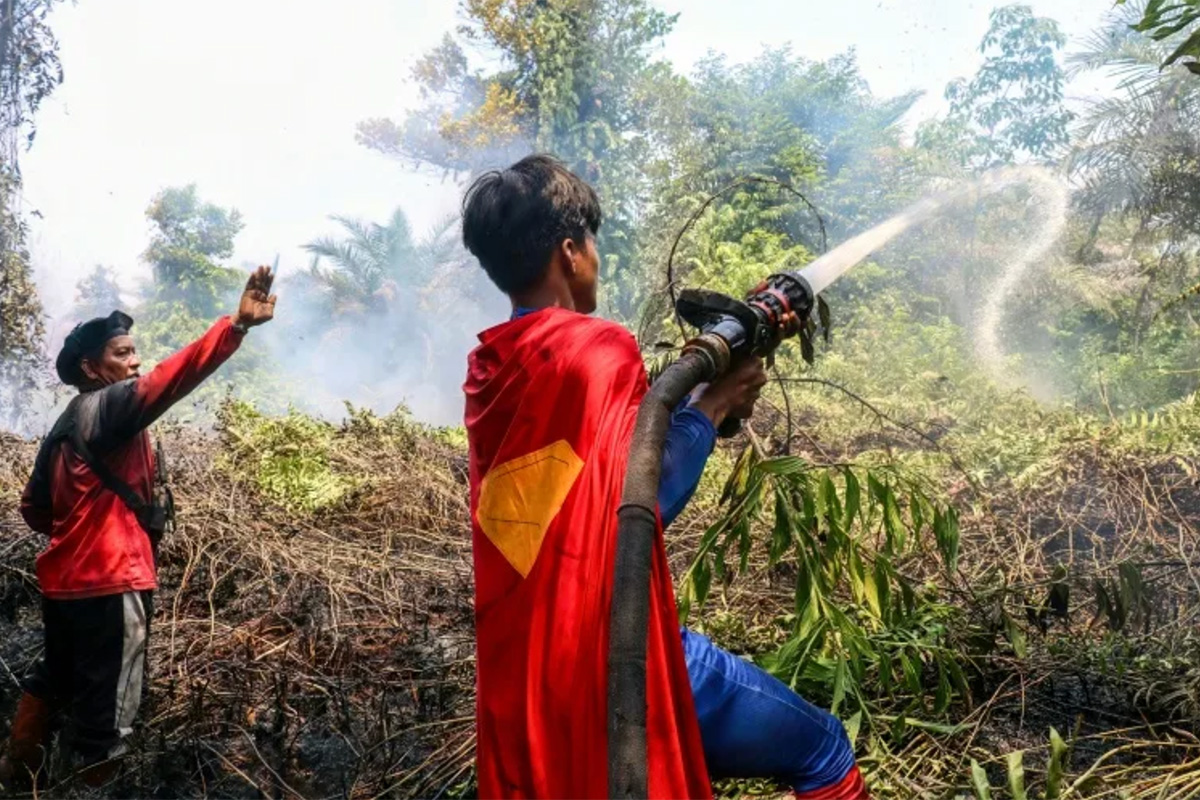Un adolescente indonesiano vestito da supereroe aiuta a spegnere i fuochi nel Borneo